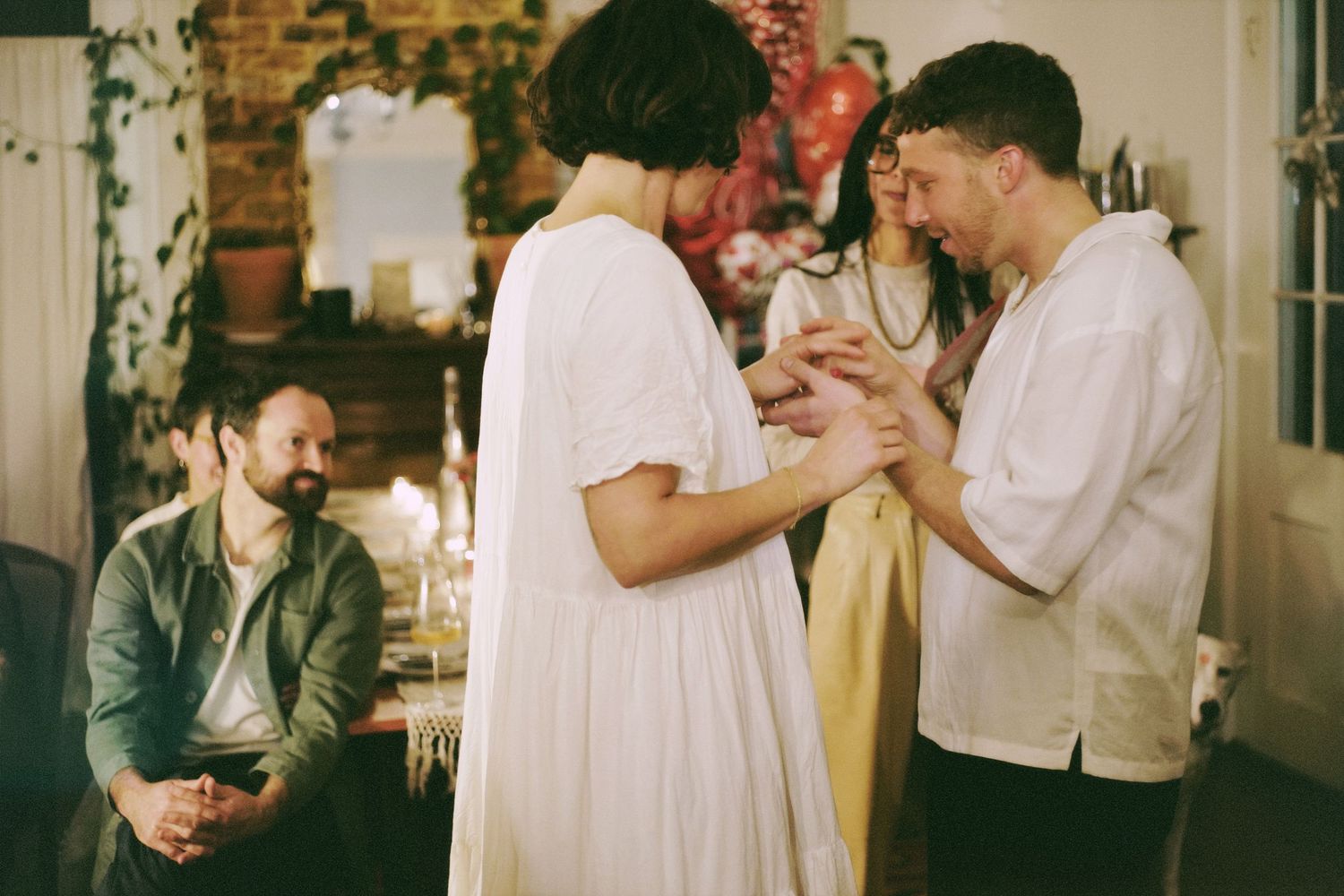 People gather at an indoor elopement with exposed brick walls and warm lighting creating a joyful atmosphere.