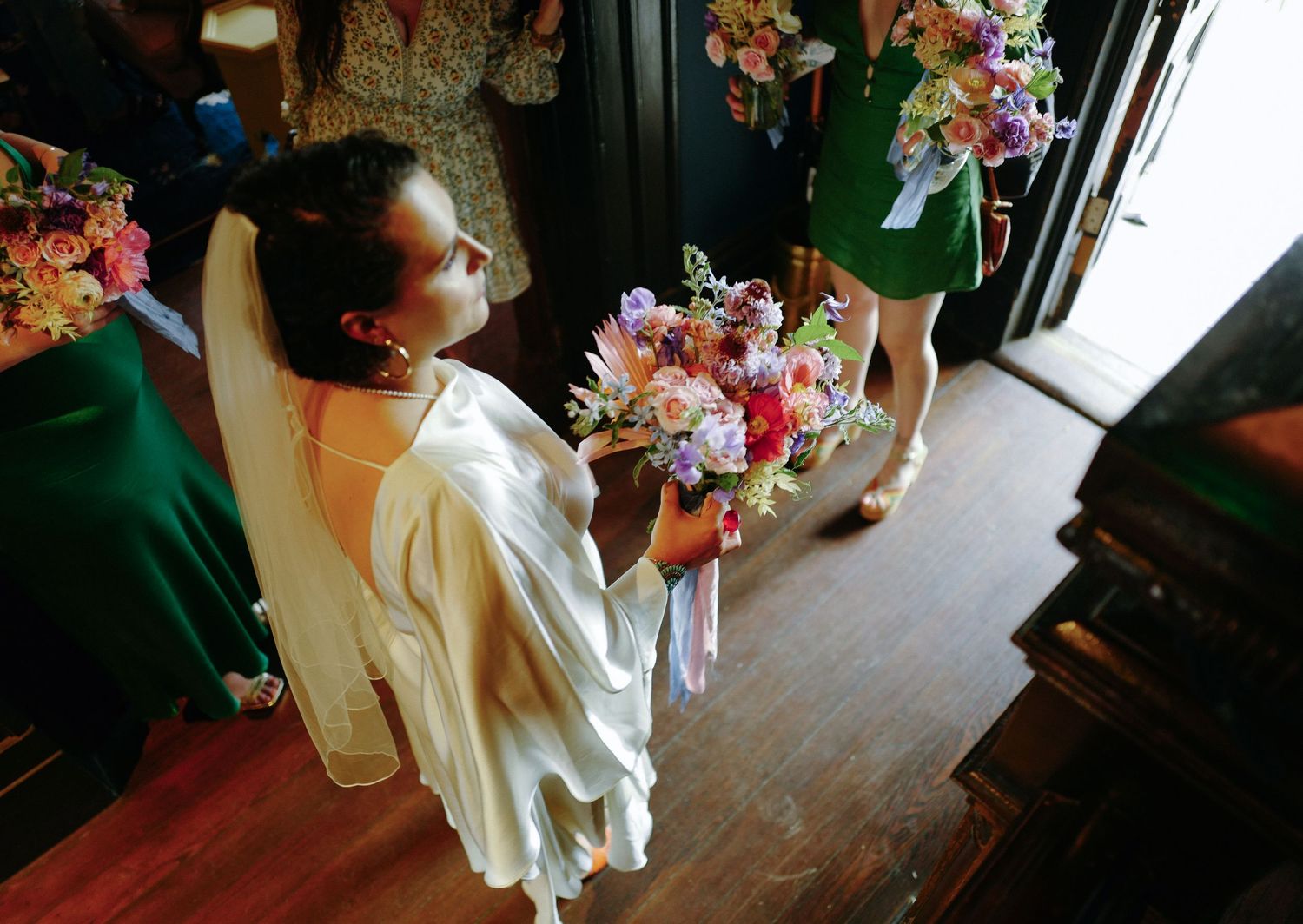 Wedding preparation scene with floral arrangements and white dress details in rustic setting.