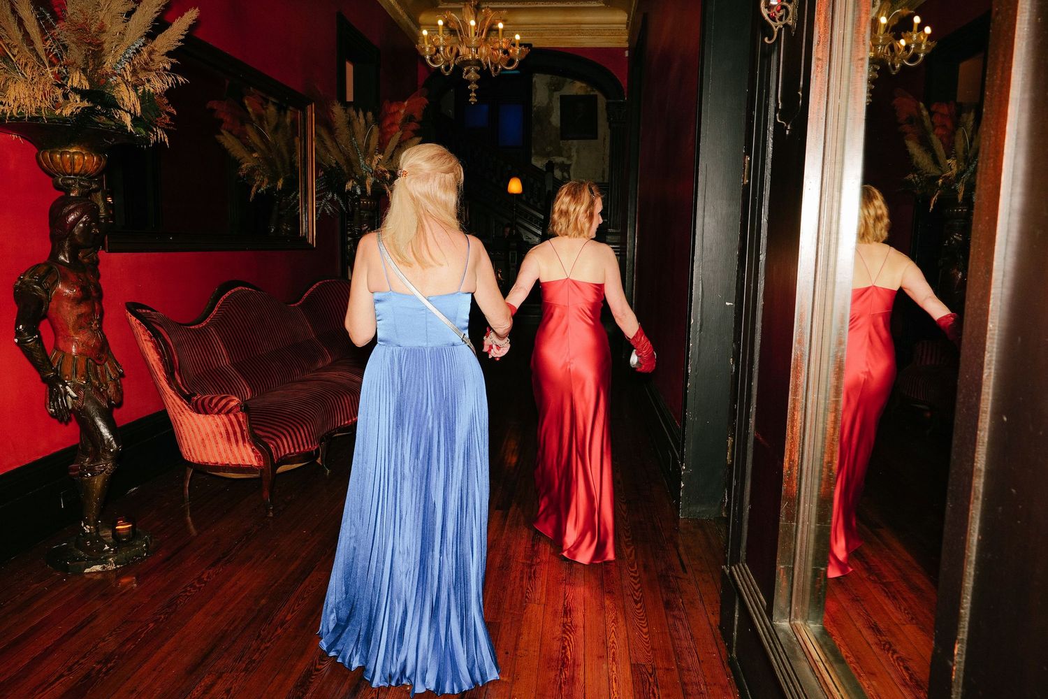 Wedding reception dance floor with guests in colorful dresses under warm lighting.