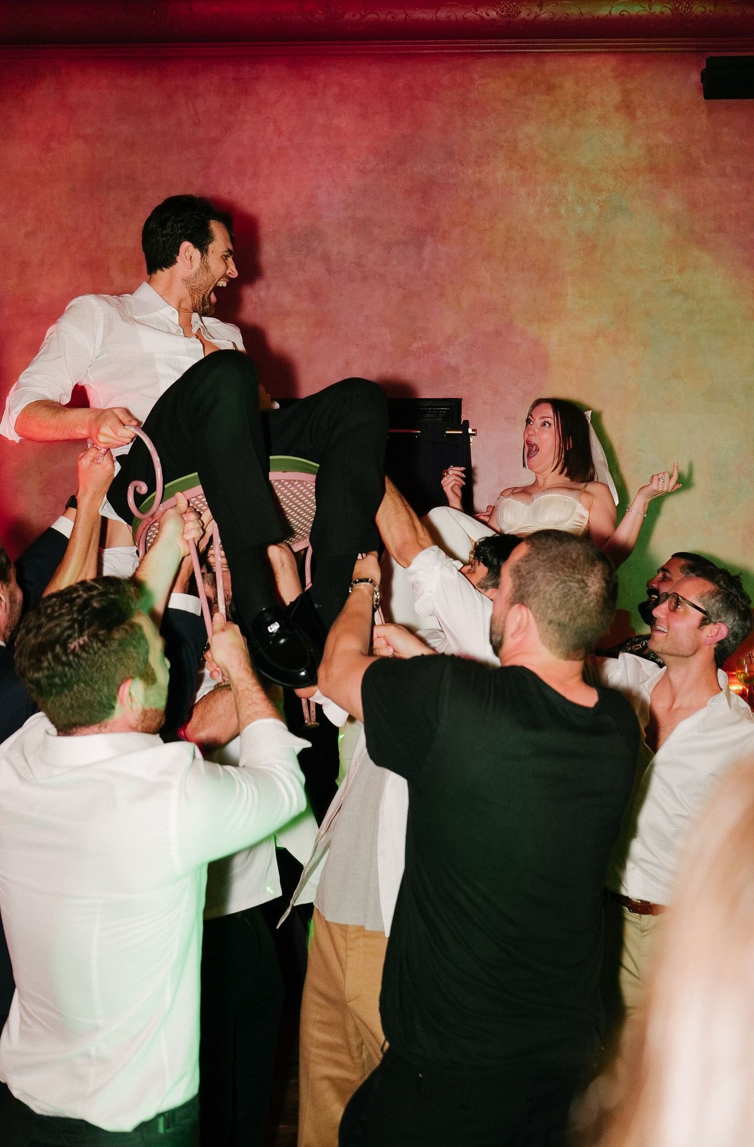 Bride and groom held up in the air by wedding guests for their Hora celebration.