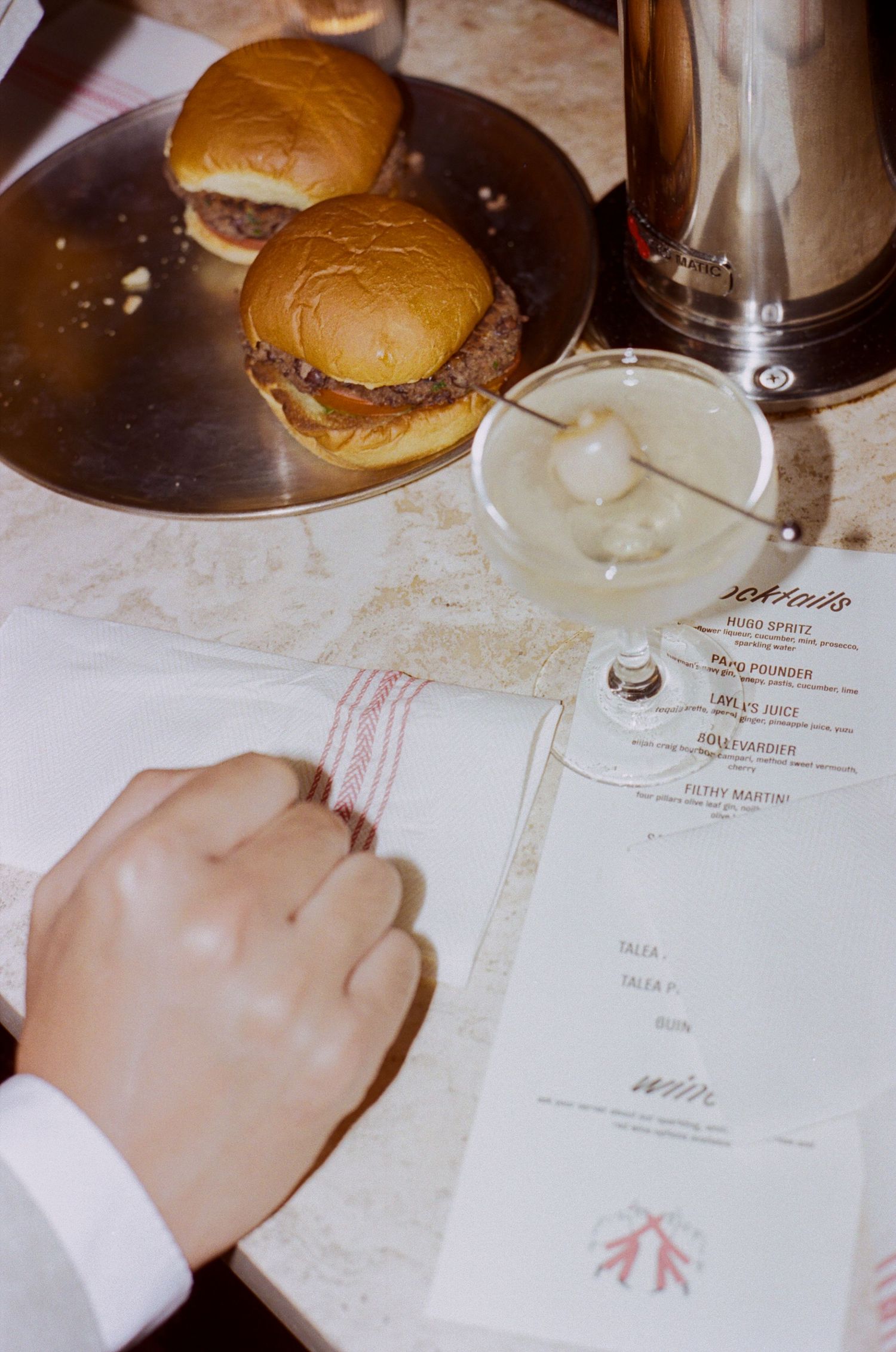 Hamburgers and menus on a white tablecloth at a wedding reception.