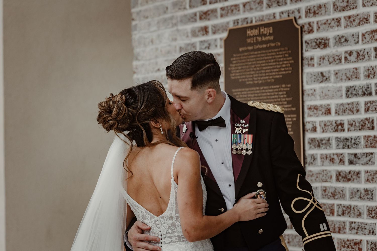 A romantic wedding couple shares intimate moments in a brick-walled venue during their special day.
