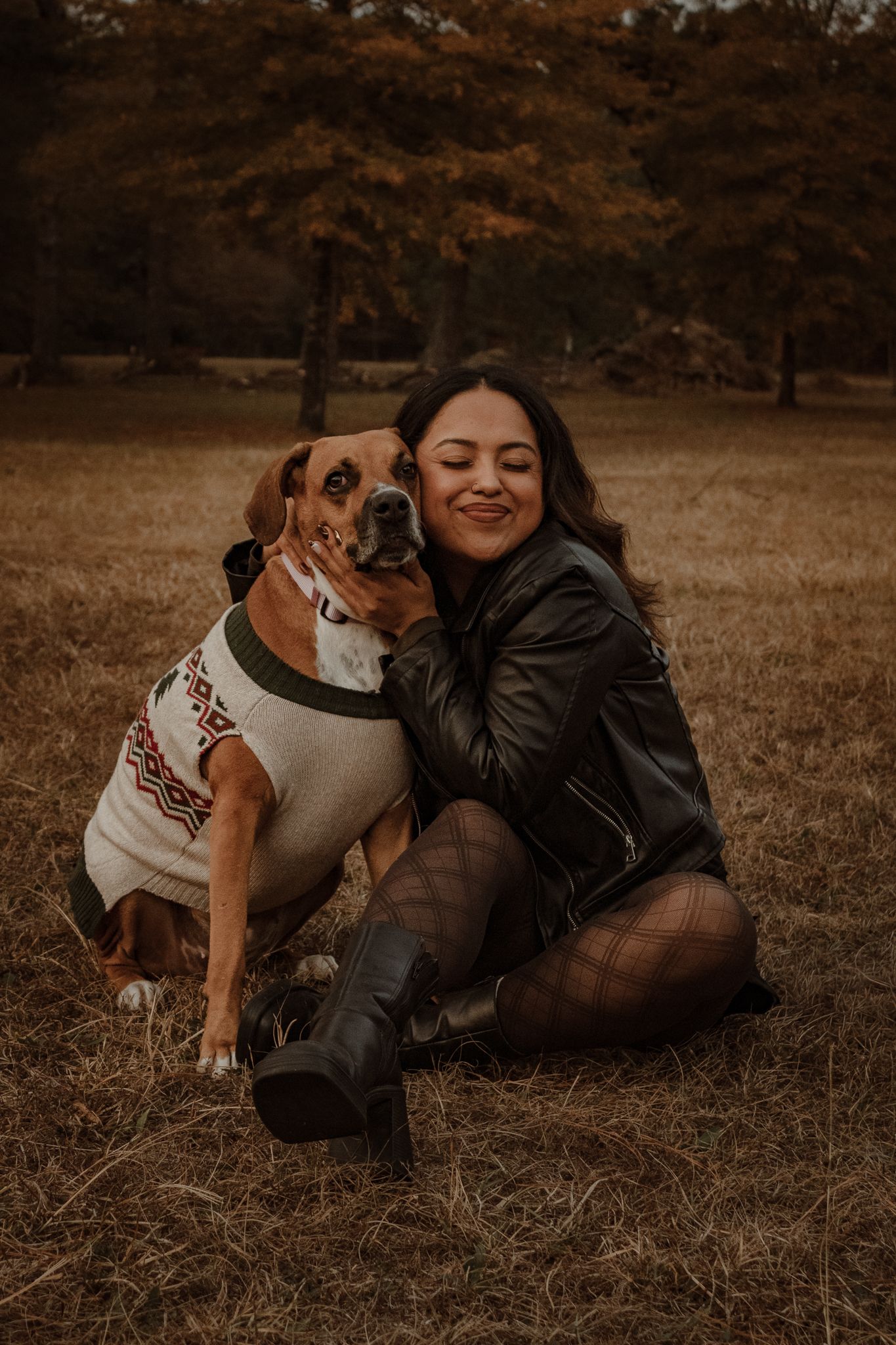 A brown and white dog plays and cuddles with someone on autumn grass in a warm sepia-toned photo series.