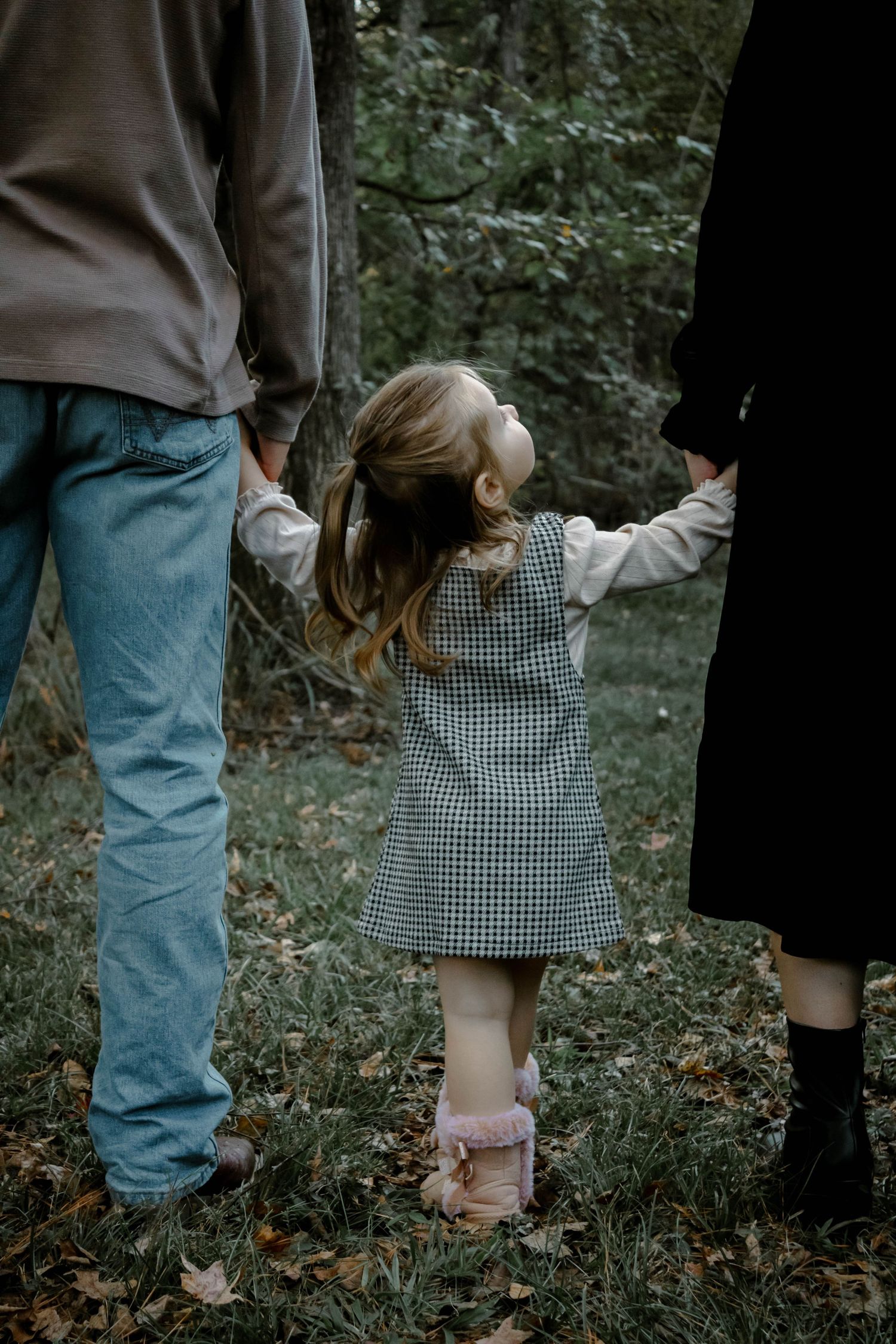 A sequence of cropped photos showing hands holding and guiding a small child walking through a wooded area.