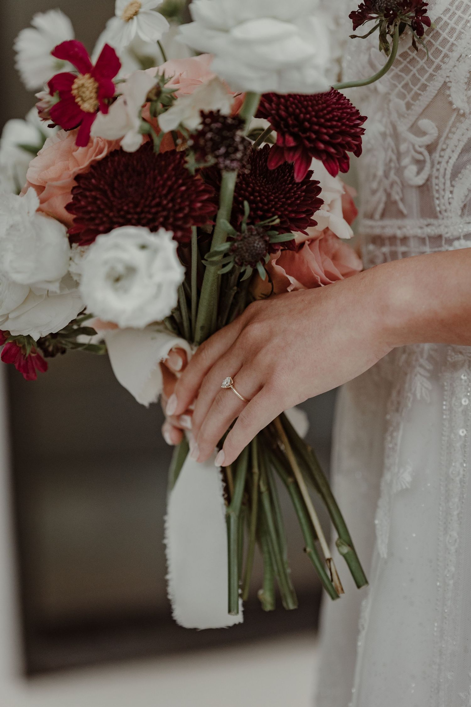 Close-up details of burgundy and white wedding bouquets with delicate lace and hands holding floral arrangements.