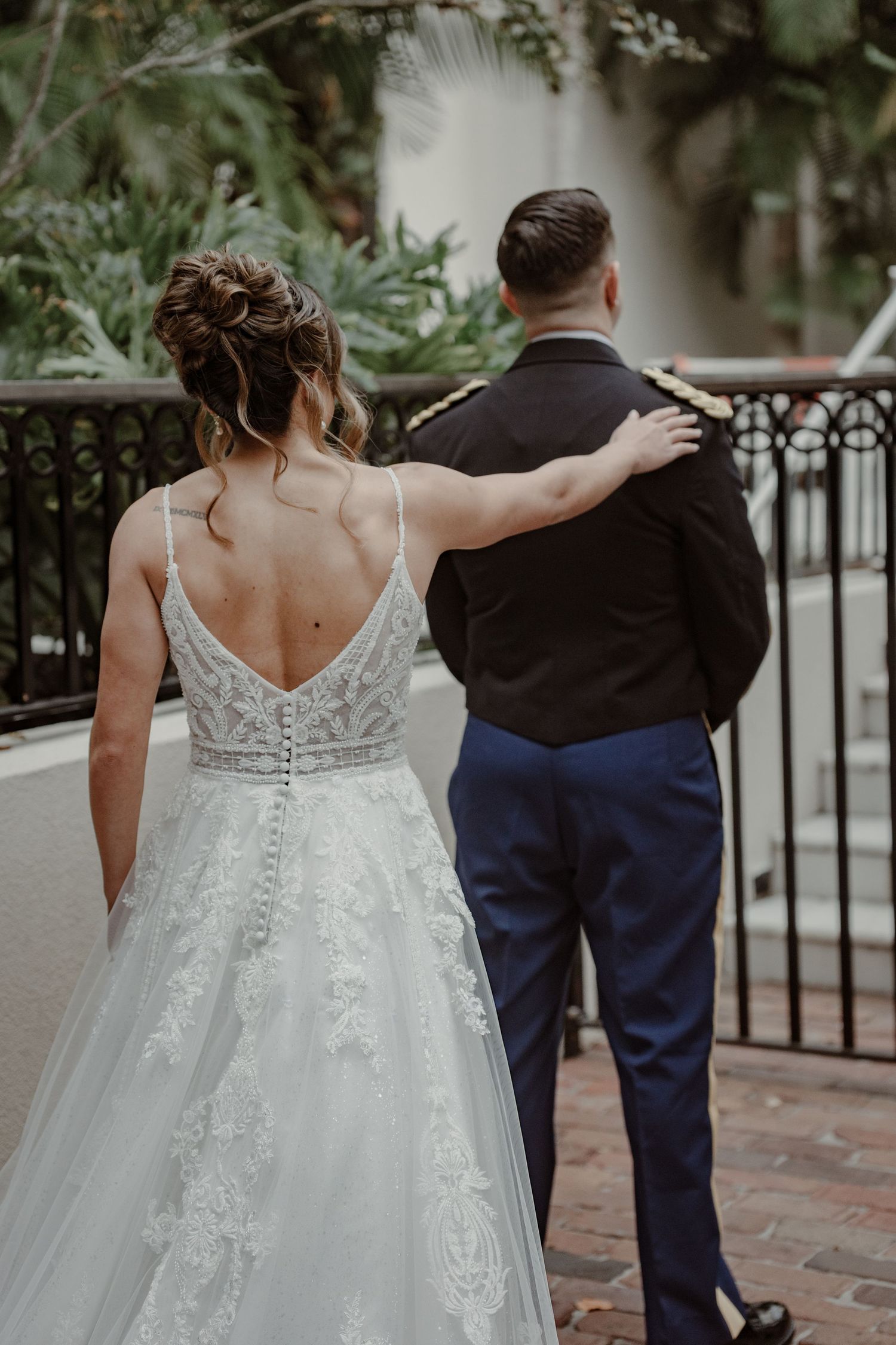 A romantic first look moment between newlyweds, with the bride's detailed lace dress and groom in navy suit.