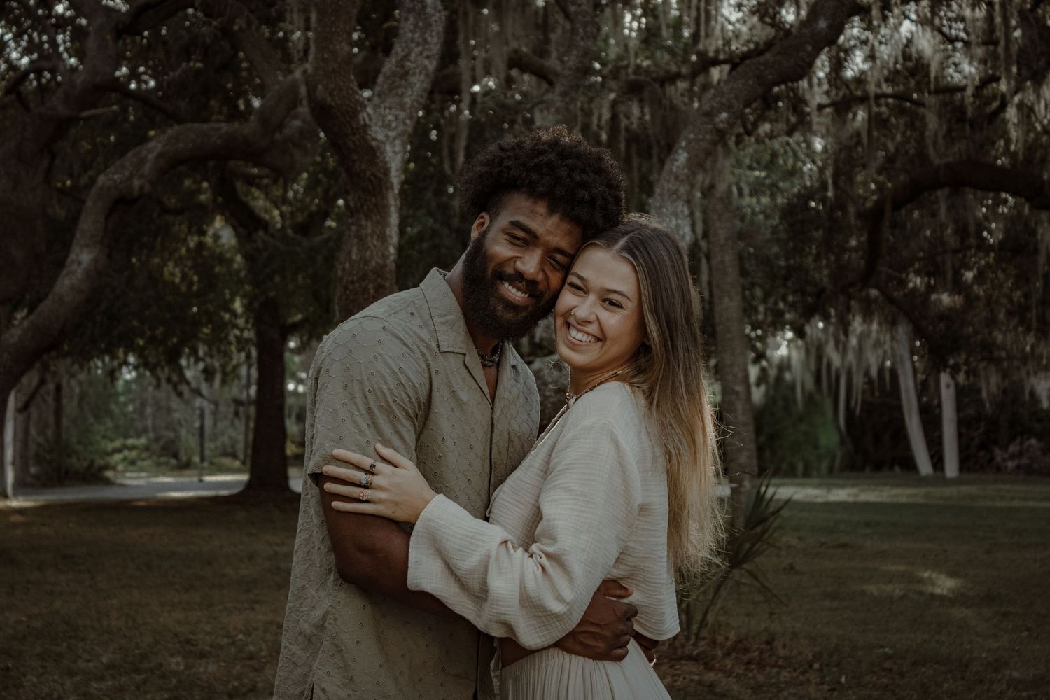 A couple embraces lovingly in a lush outdoor garden setting during a romantic photoshoot.