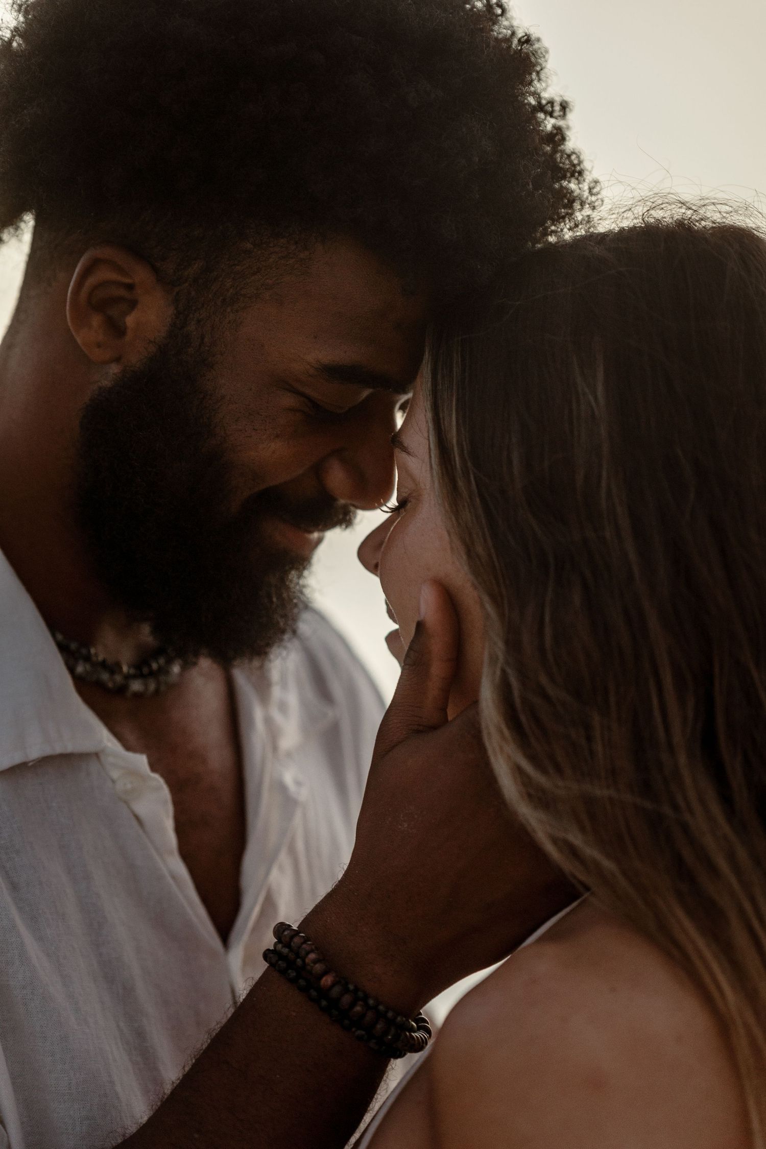 Silhouetted couple shares tender close-up moments in warm natural lighting.