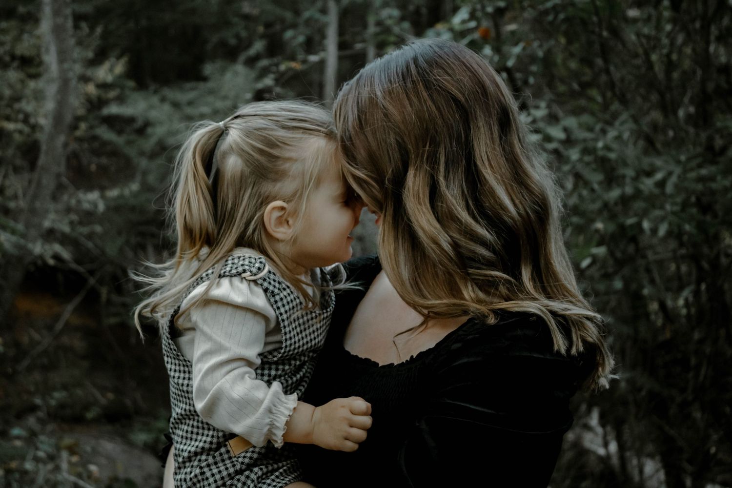 A series of intimate black and white photographs showing tender moments between parent and child in a natural setting.