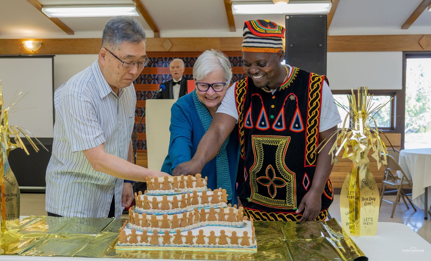 People gathered around a table working on assembling a gingerbread house structure.