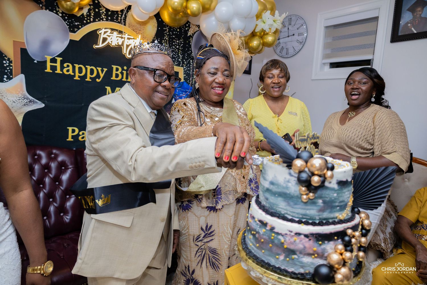 Birthday party scene with gold balloons and tiered cake on display.
