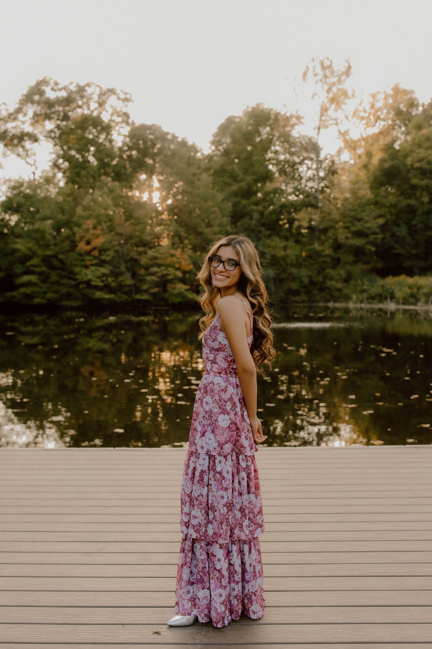 Portrait session on a wooden deck overlooking a serene pond at sunset.