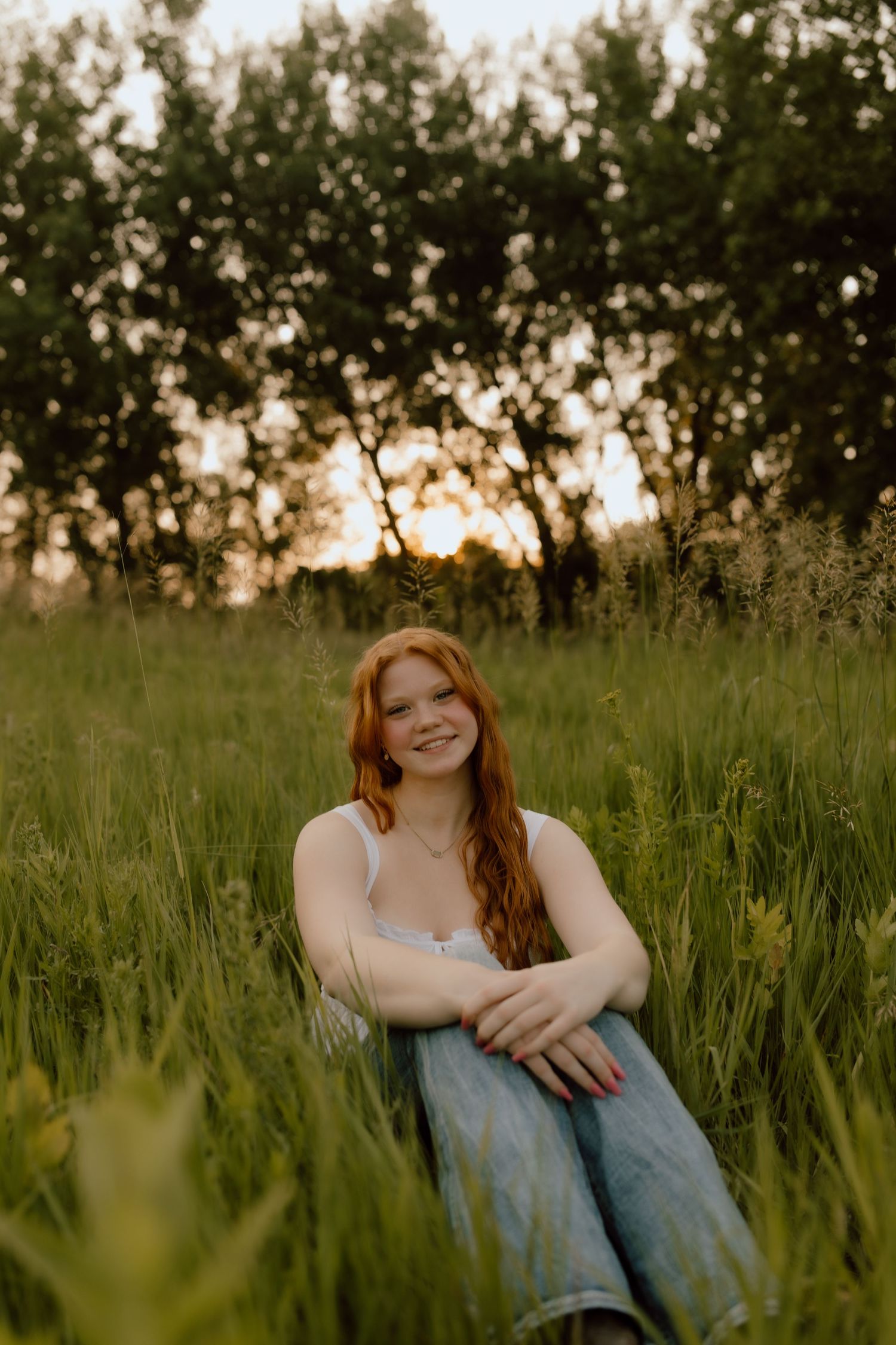 Natural light portrait in tall grass during golden hour with casual summer styling.