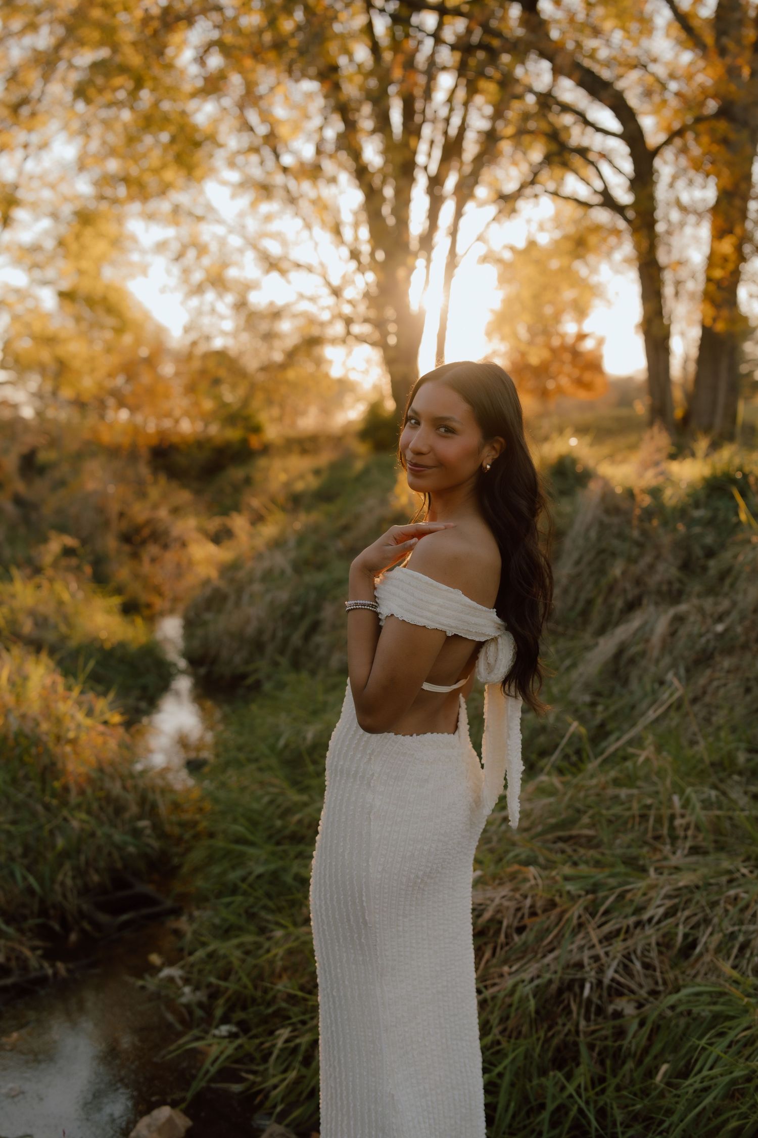 White dress contrasts beautifully with natural scenery during golden hour photoshoot.