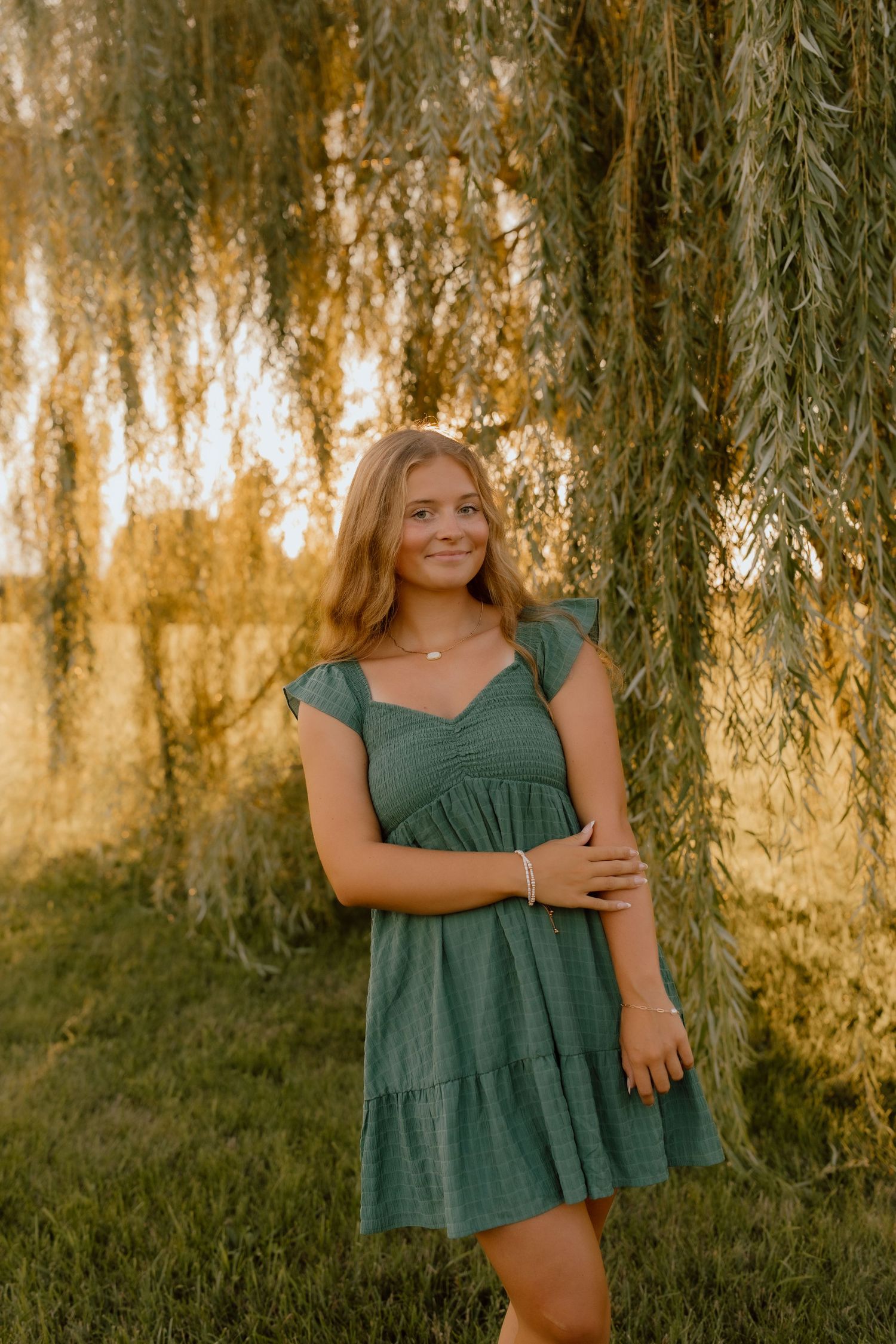 Portrait under a weeping willow tree in a green summer dress.