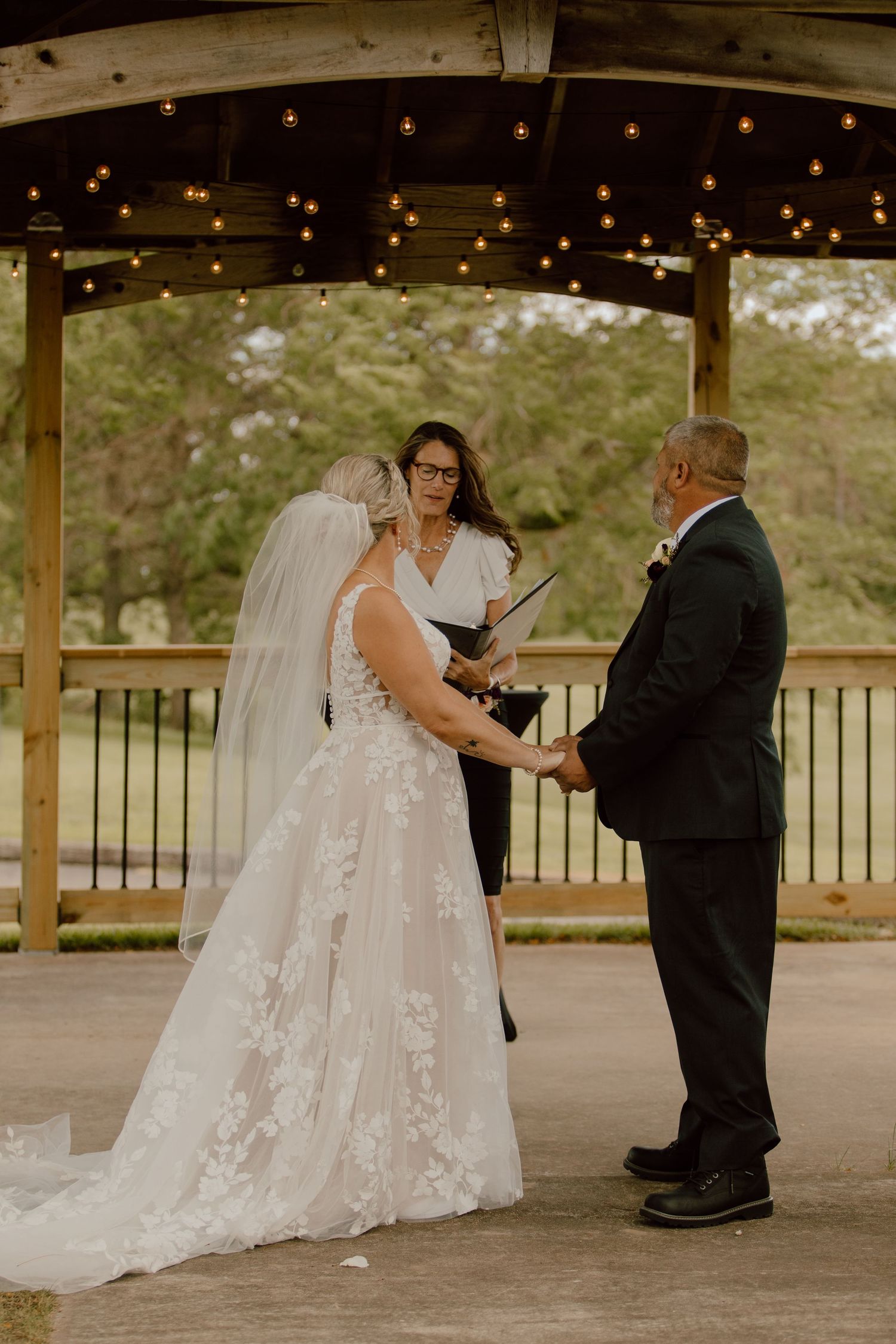 A wedding couple shares an intimate dance moment under a covered pavilion.