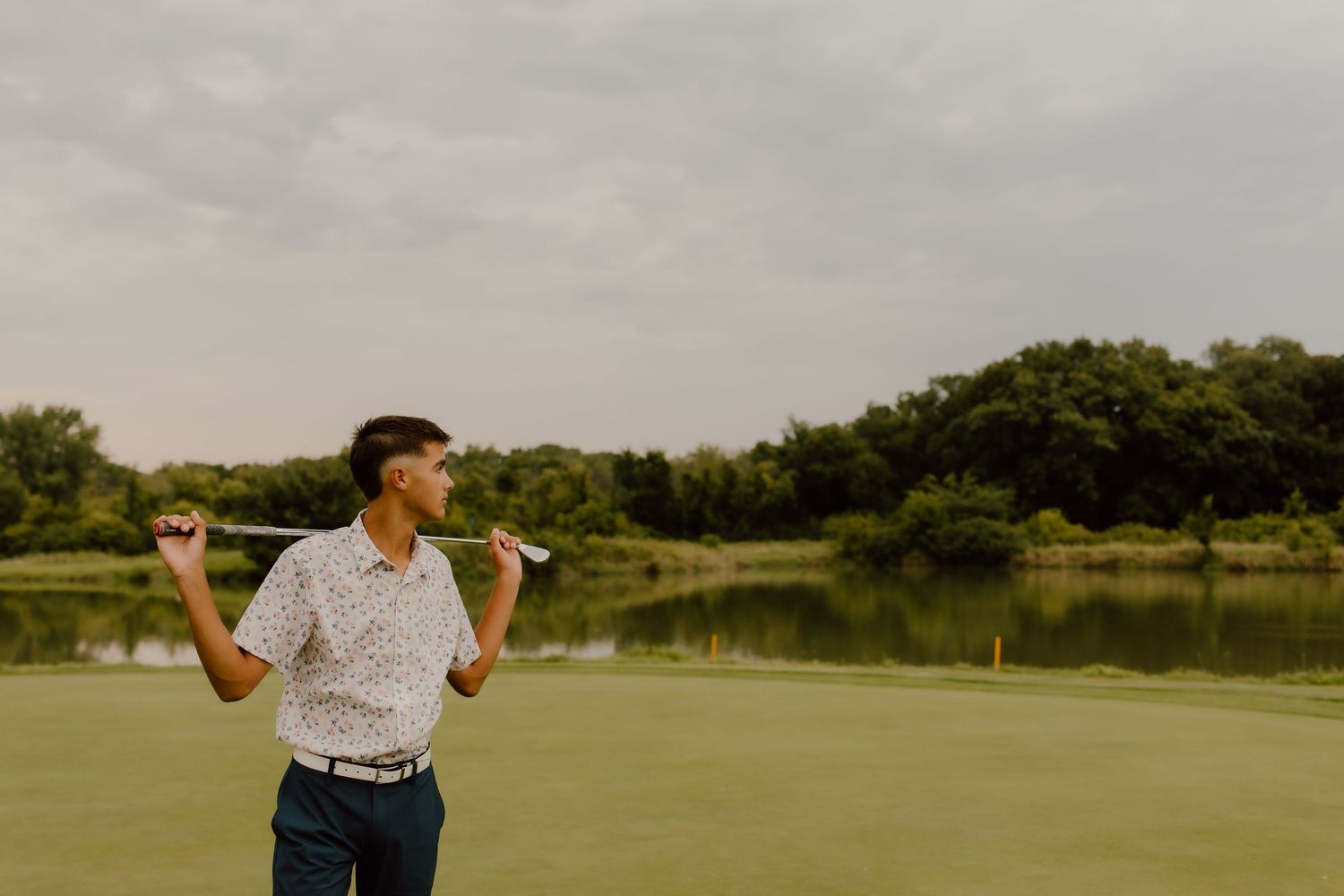 Golfer celebrating on a green course with water hazard in background.