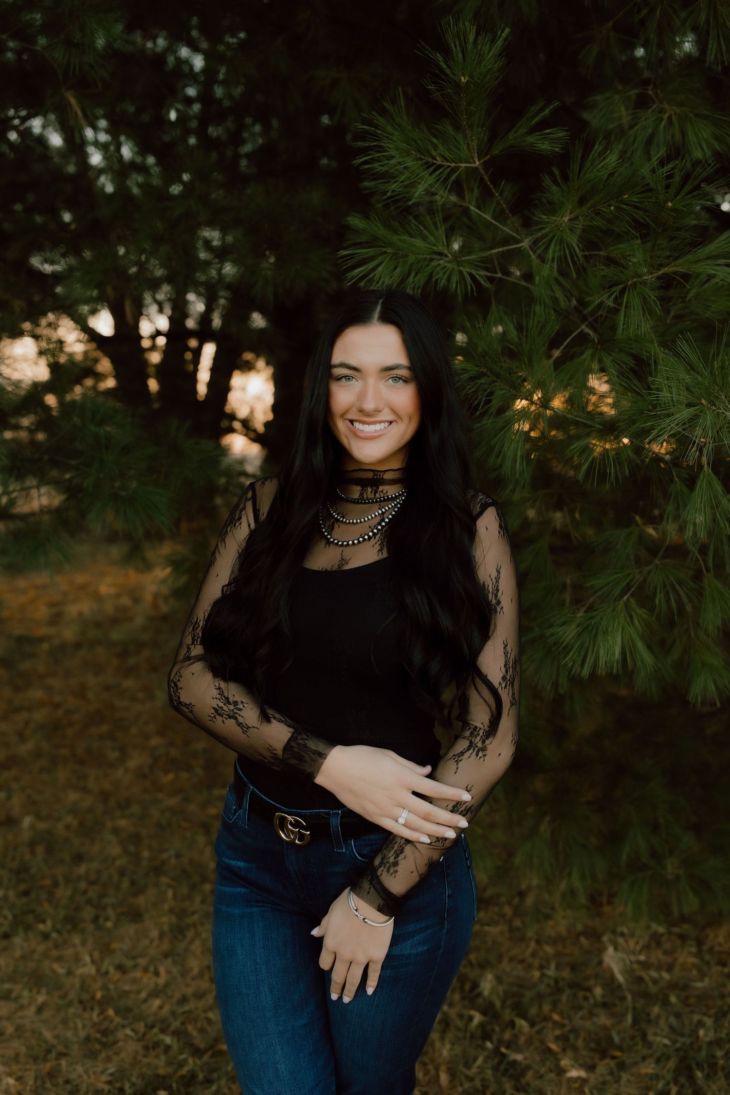 Outdoor portrait with pine trees and sunset lighting in the background.