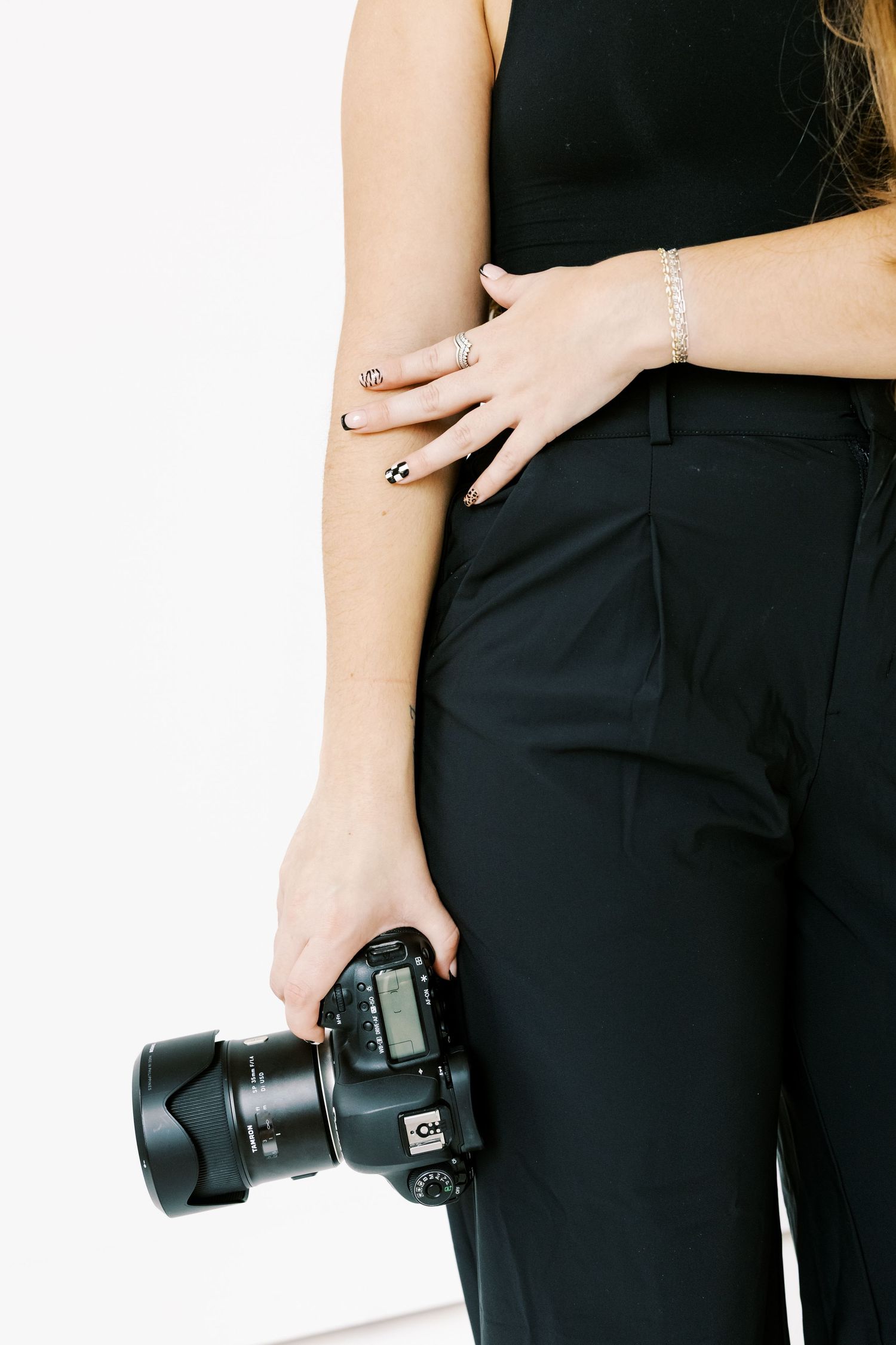 Close-up shots of hands holding a professional camera lens against black clothing.