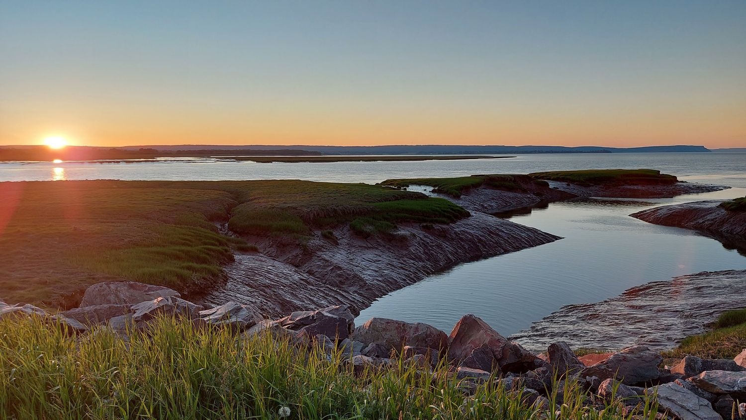 Sunset in the distance of the Wolfville, NS muddy tidal bay 
Photo Credit: Shelley Thompson