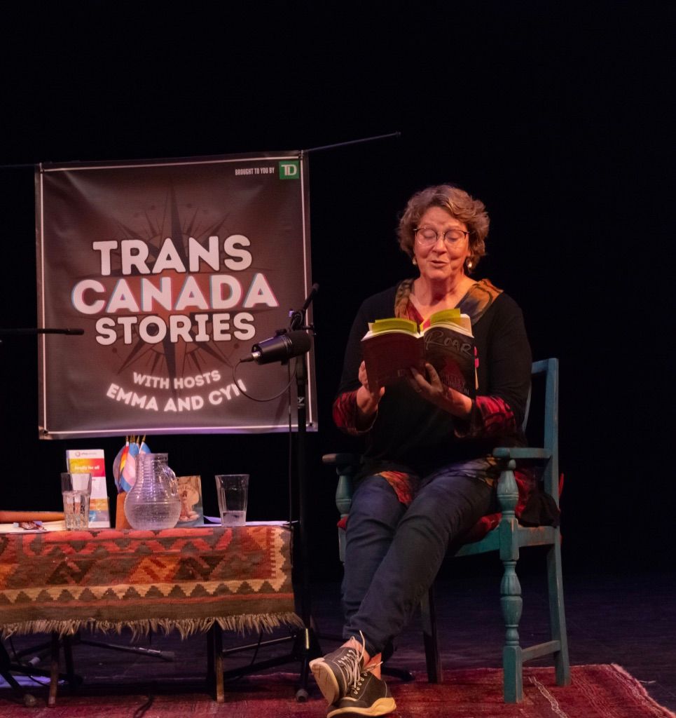 Shelley Thompson reading from ROAR in a black box theatre with a sign that reads 