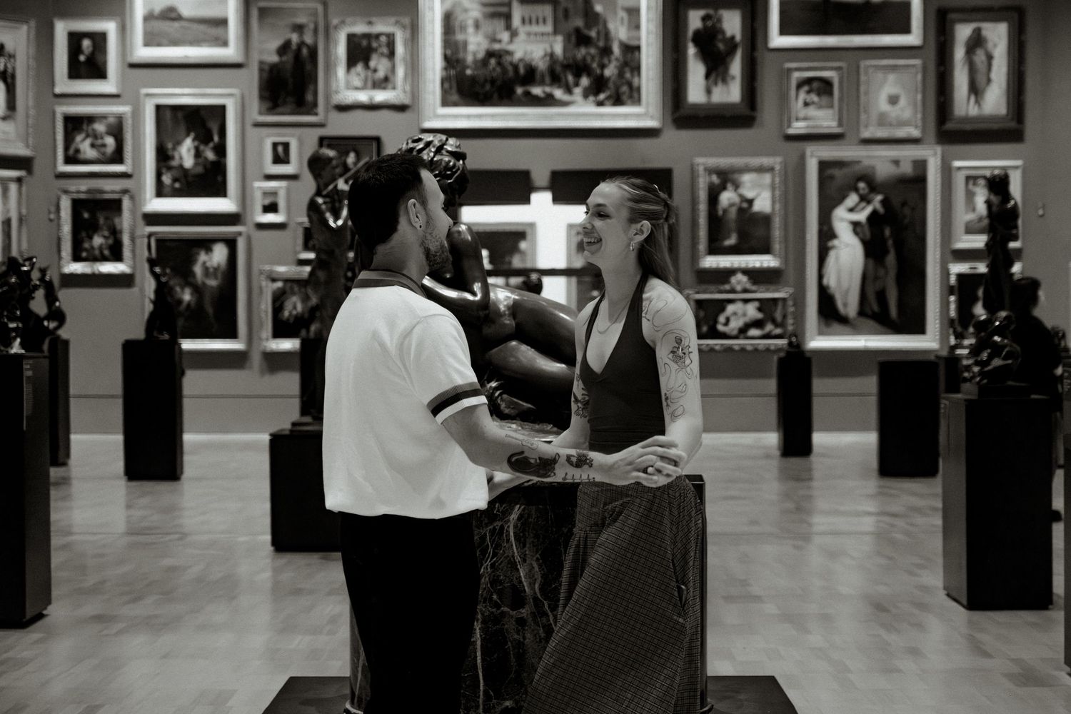 Warrnambool couples photographer captures black and white photo of a couple holding hands and smiling in an art gallery.