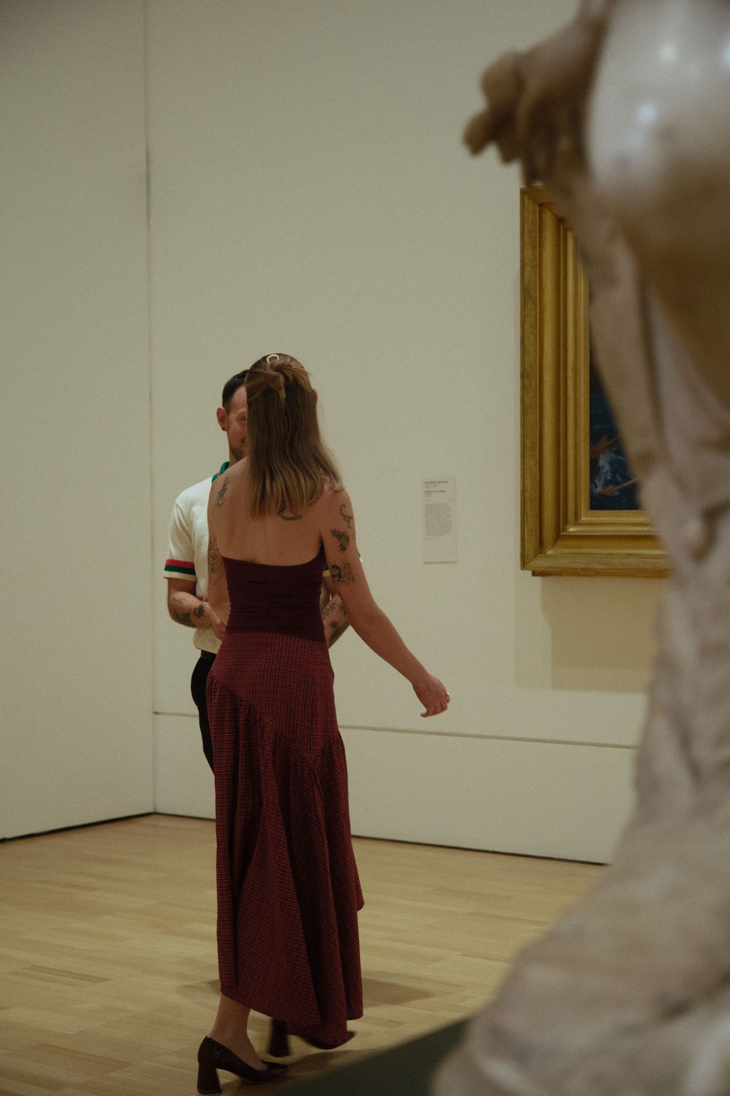 Couple embracing while viewing artwork in a bright museum gallery.