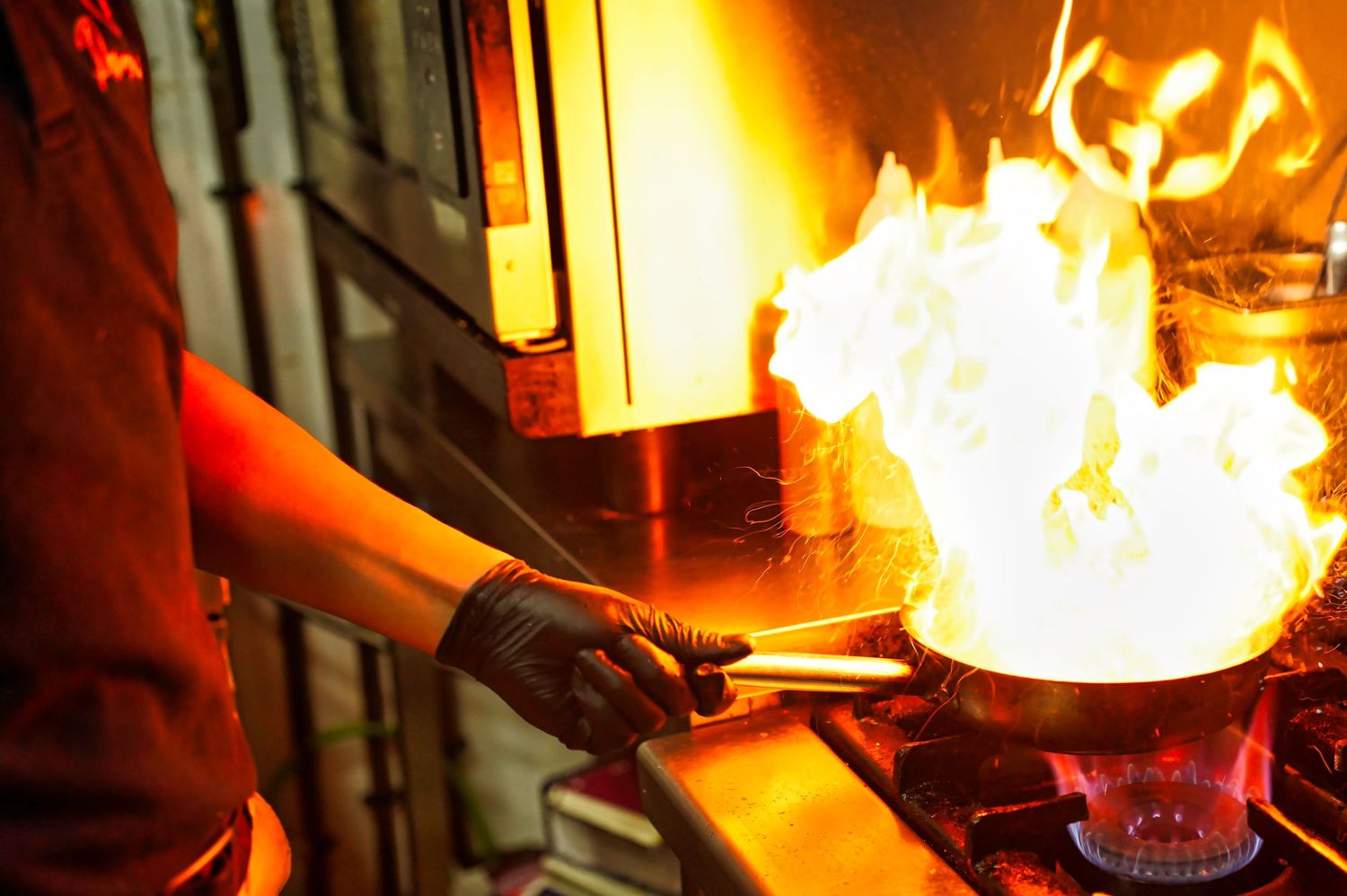 Chef cooking with dramatic flames in wok at professional kitchen.