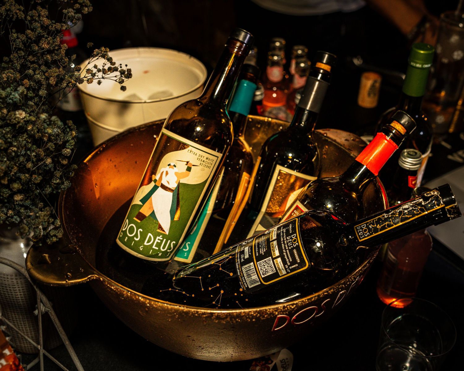 Dark moody bar setup with bottles and glassware illuminated by ambient lighting.
