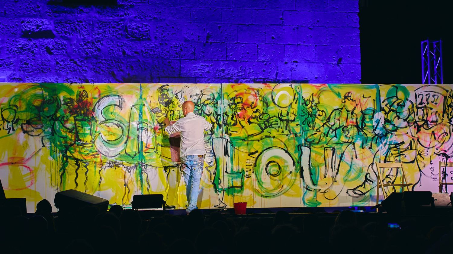 Colorful graffiti mural spanning across a blue-lit wall background.