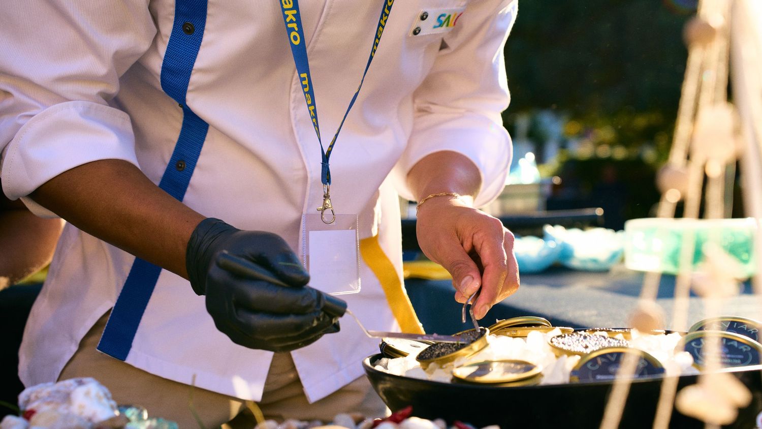 Close-up of hands preparing food at an outdoor catering station.