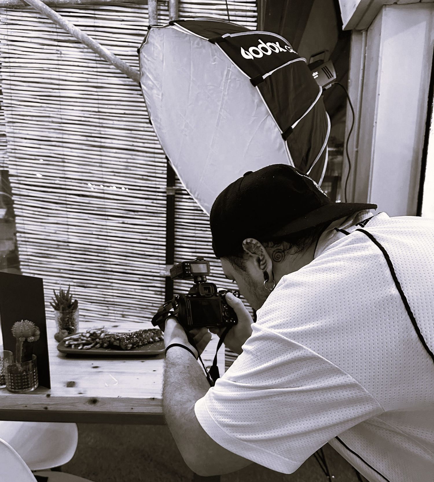 A photographer in a white shirt taking close-up shots in black and white.