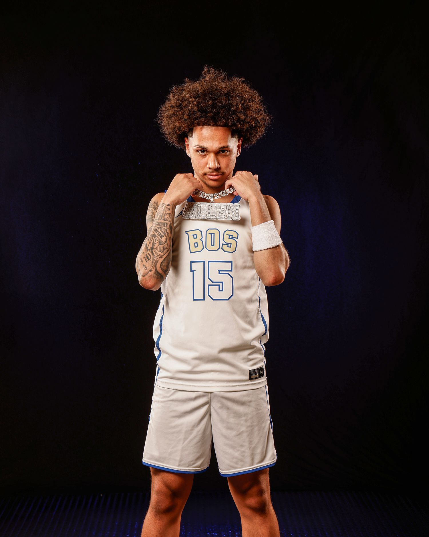 Basketball player in BOS #15 jersey poses confidently with fists raised in studio.