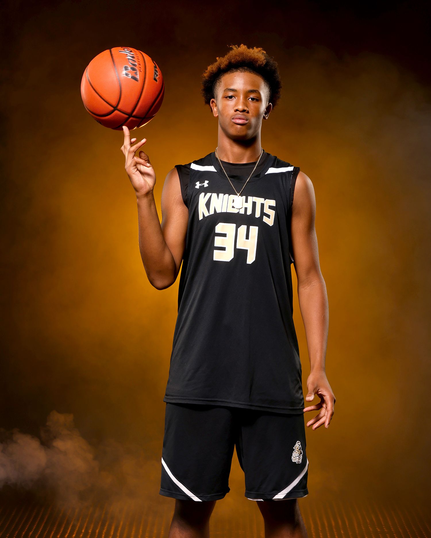 Knights #34 basketball player balances ball on finger in golden smoky studio.