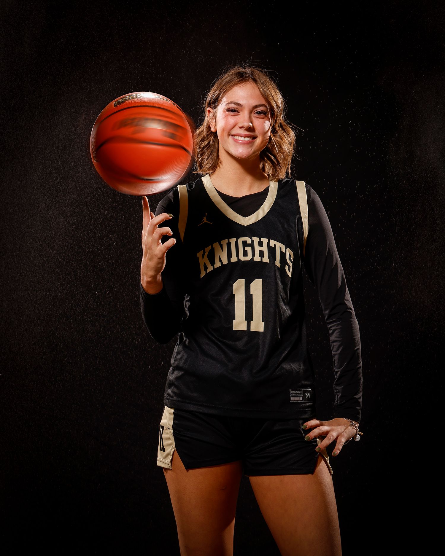 Knights #11 basketball player spins ball on finger in studio portrait.