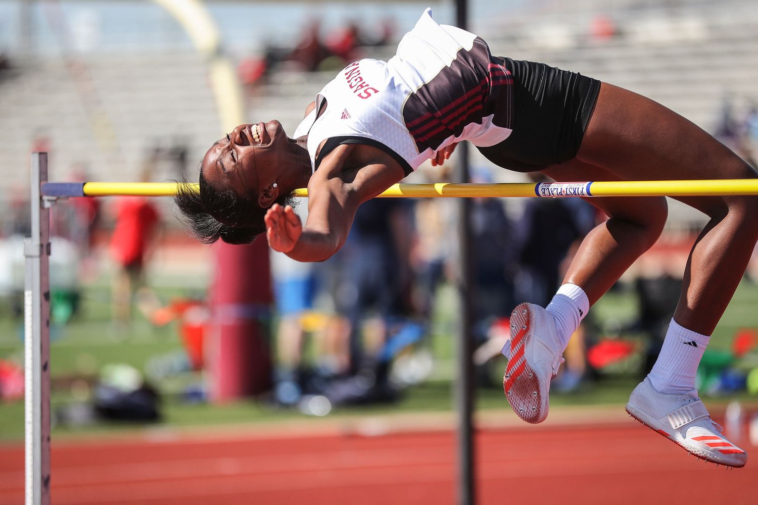 Athlete performs high jump over bar at outdoor track meet.