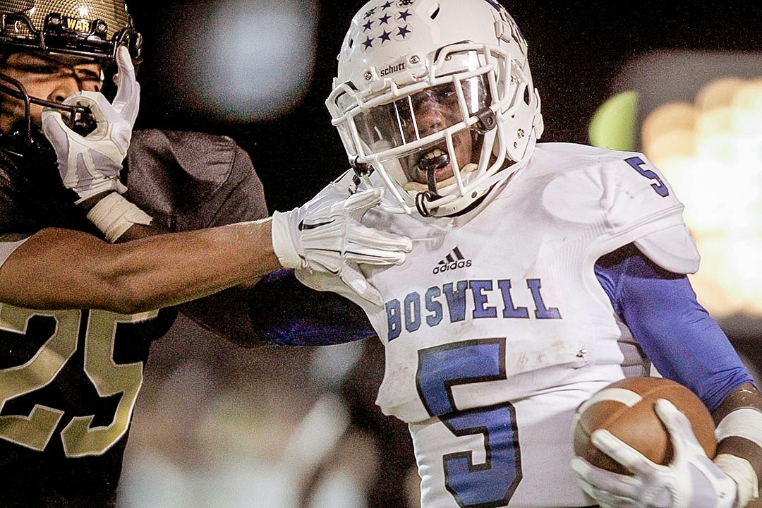 Boswell high school football player number 5 breaks tackle during intense night game action.