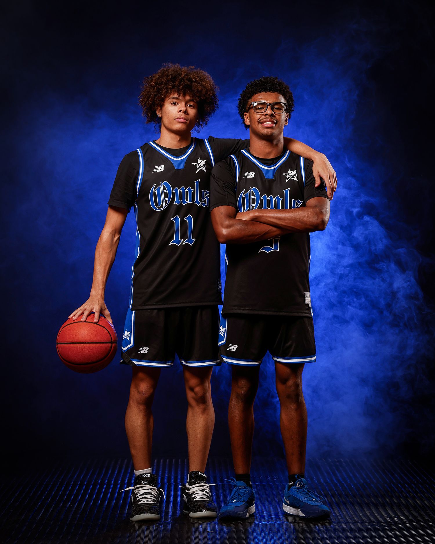 Two Owls basketball players pose together in blue-lit smoky studio.