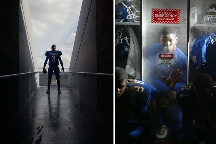Football player in blue uniform stands in stadium tunnel as teammates gear up in locker room.