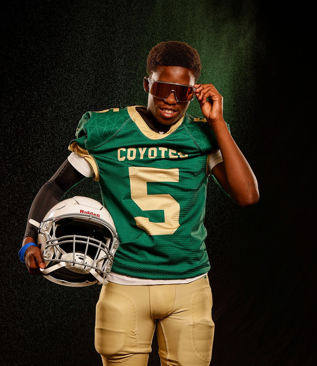 Coyotes football player #5 poses in green jersey with sunglasses and helmet.