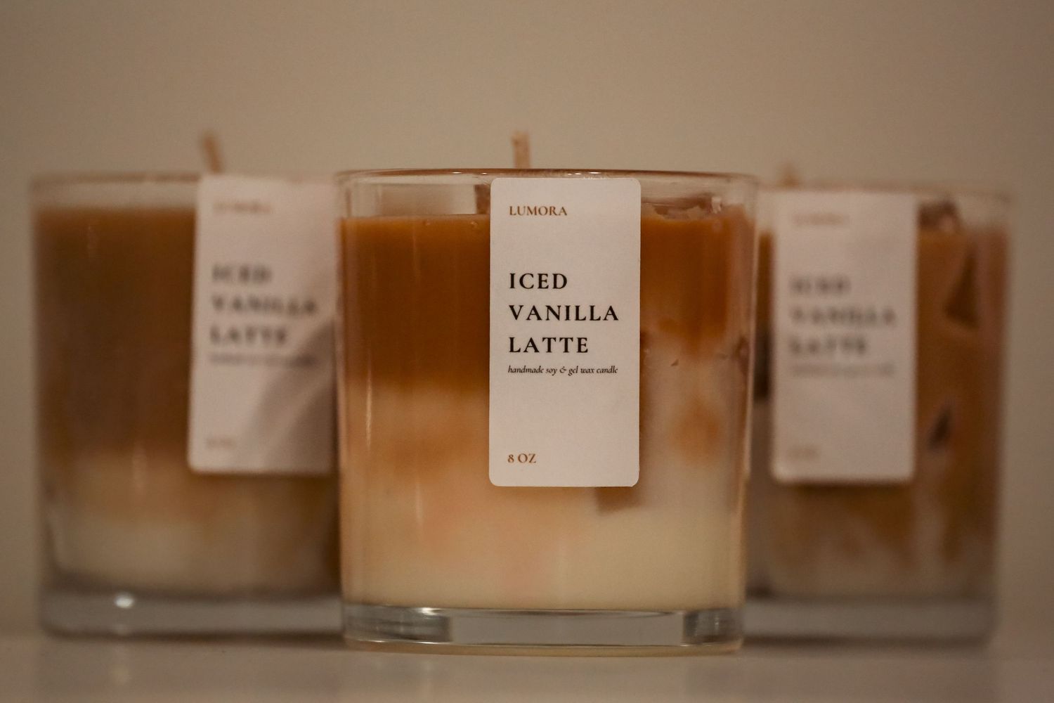 Close-up of Lumora Iced Vanilla Latte handmade soy wax candles with caramel layered wax in glass.