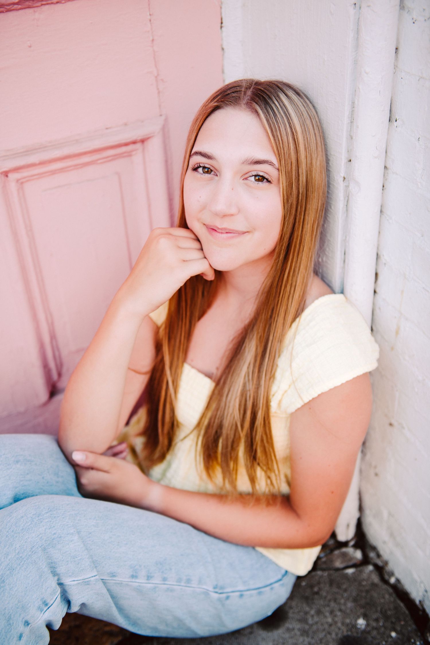 high school senior girl pictures leaning against pink door
