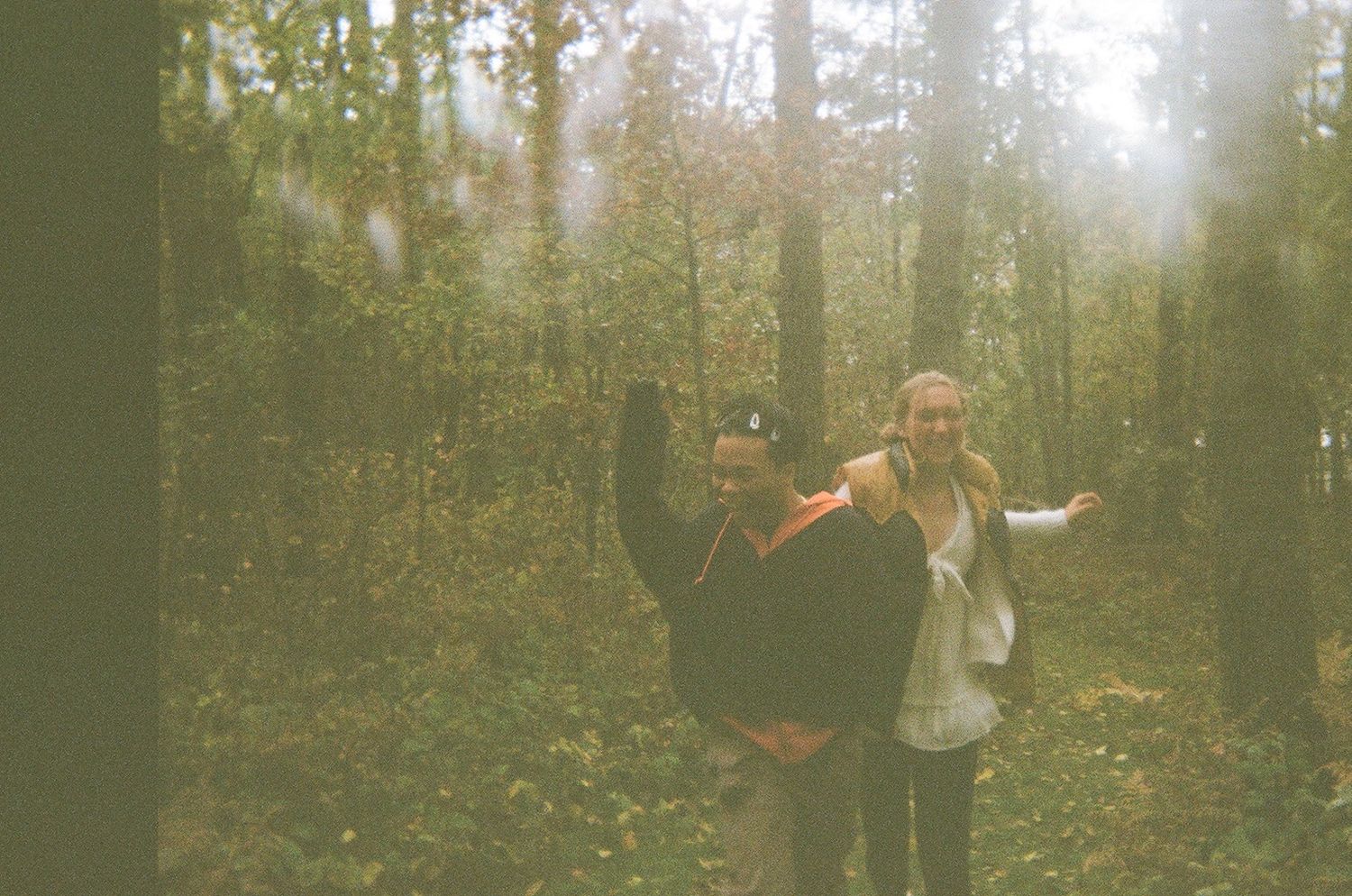 film photo of two friends running through the woods