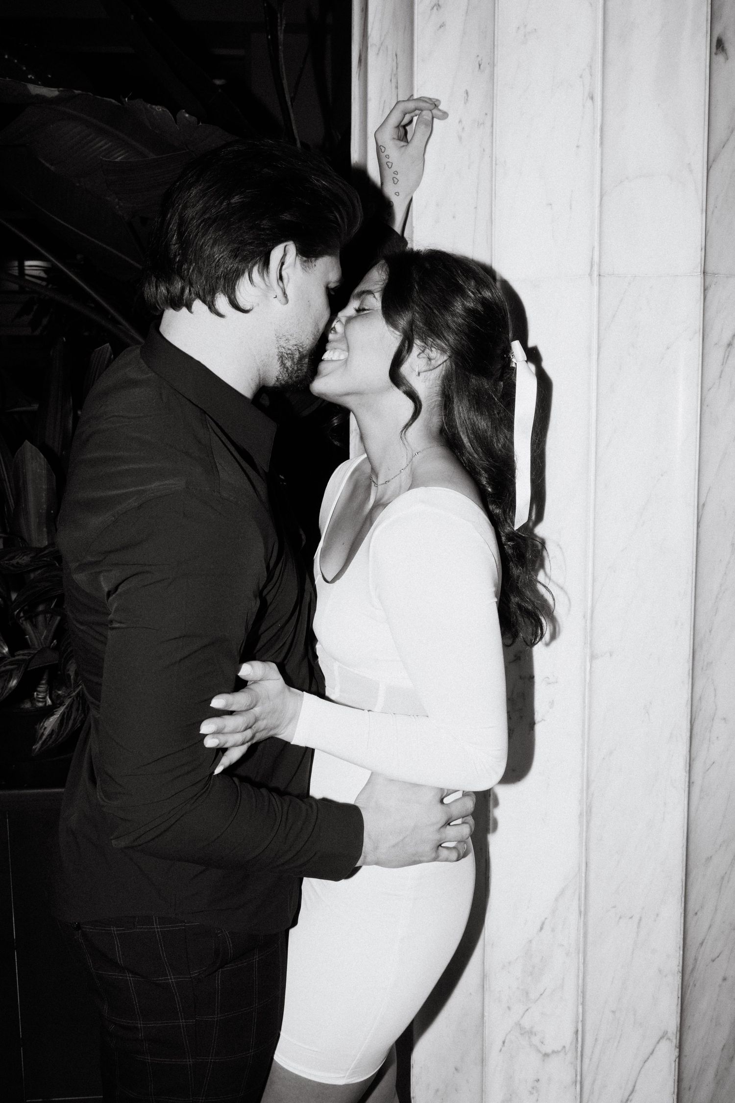 engagement photo of couple with direct flash in front of marble wall at hotel in minneapolis