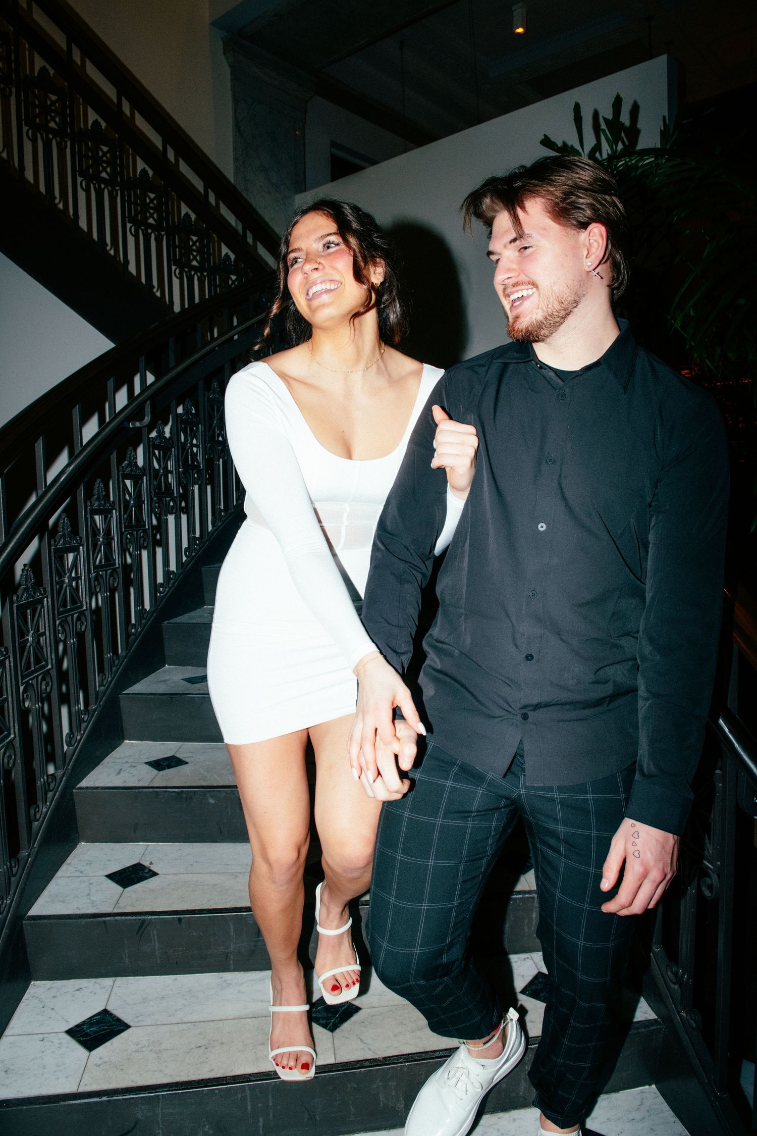 engagement photo of couple with direct flash walking down marbled stairs in hotel in minneapolis