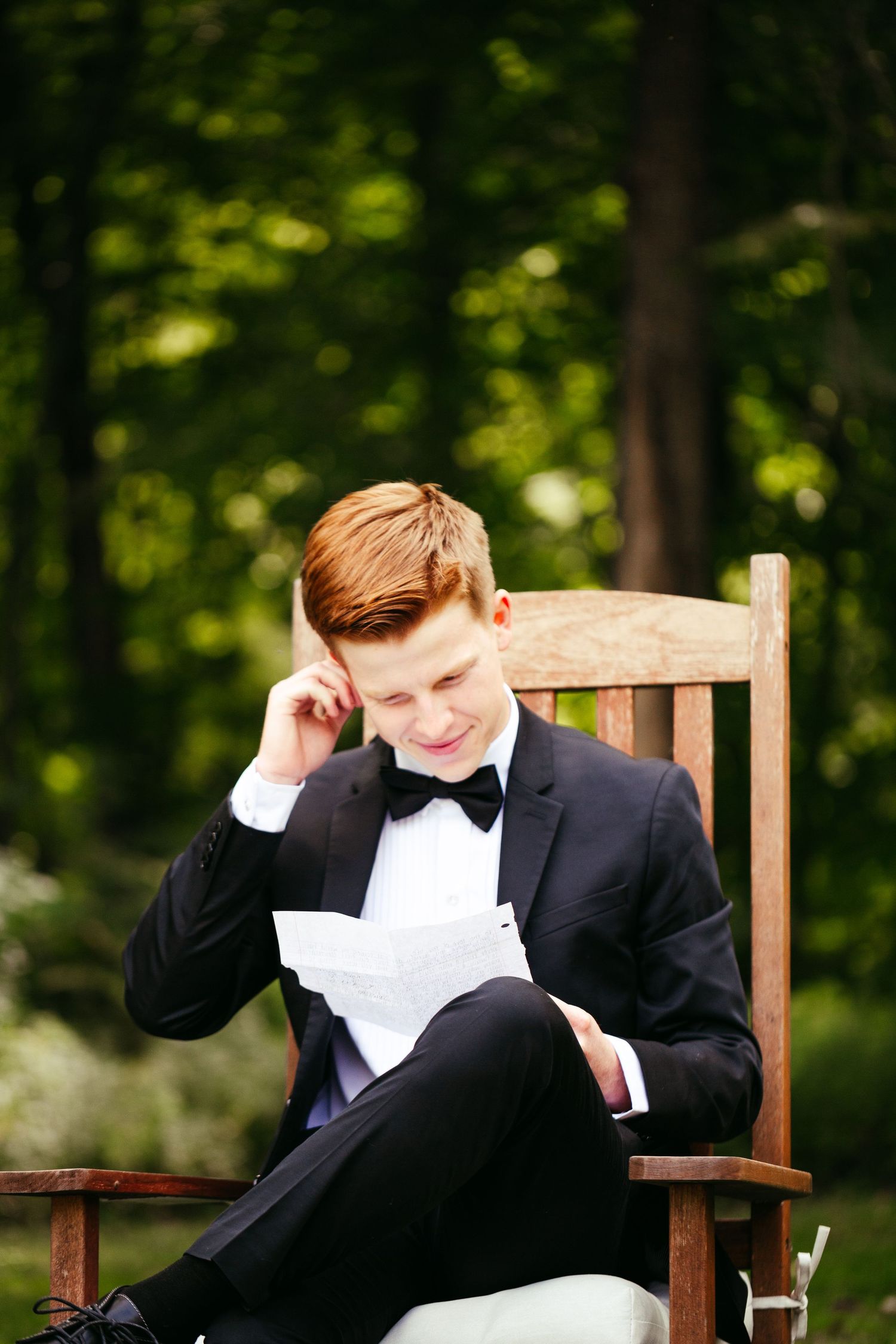 groom sitting in chair reading a letter