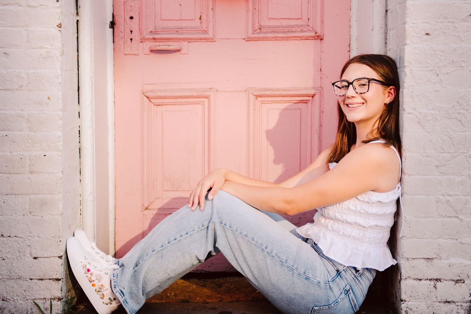 high school senior leaning against pink door