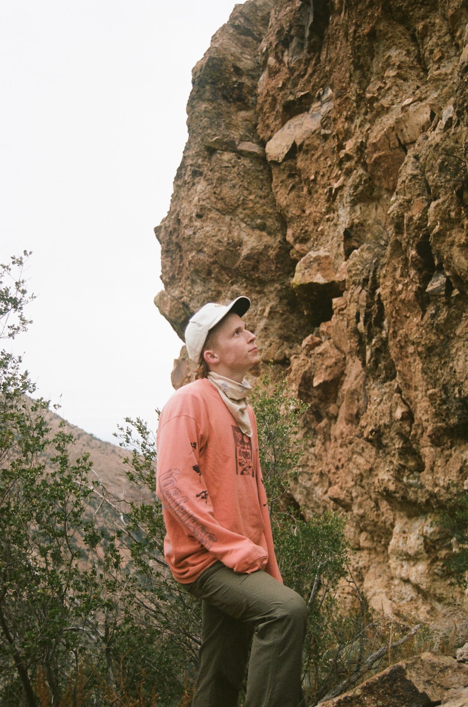 film photo of man standing looking up at mountain