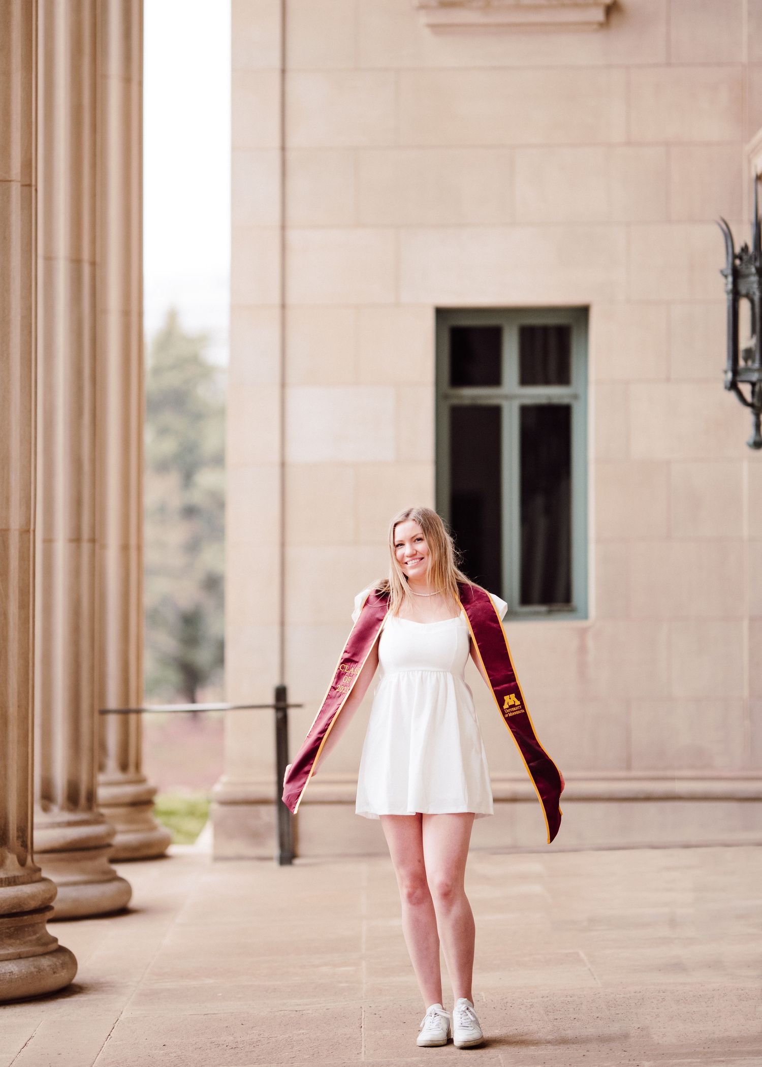 university of minnesota graduate in white dress with sash