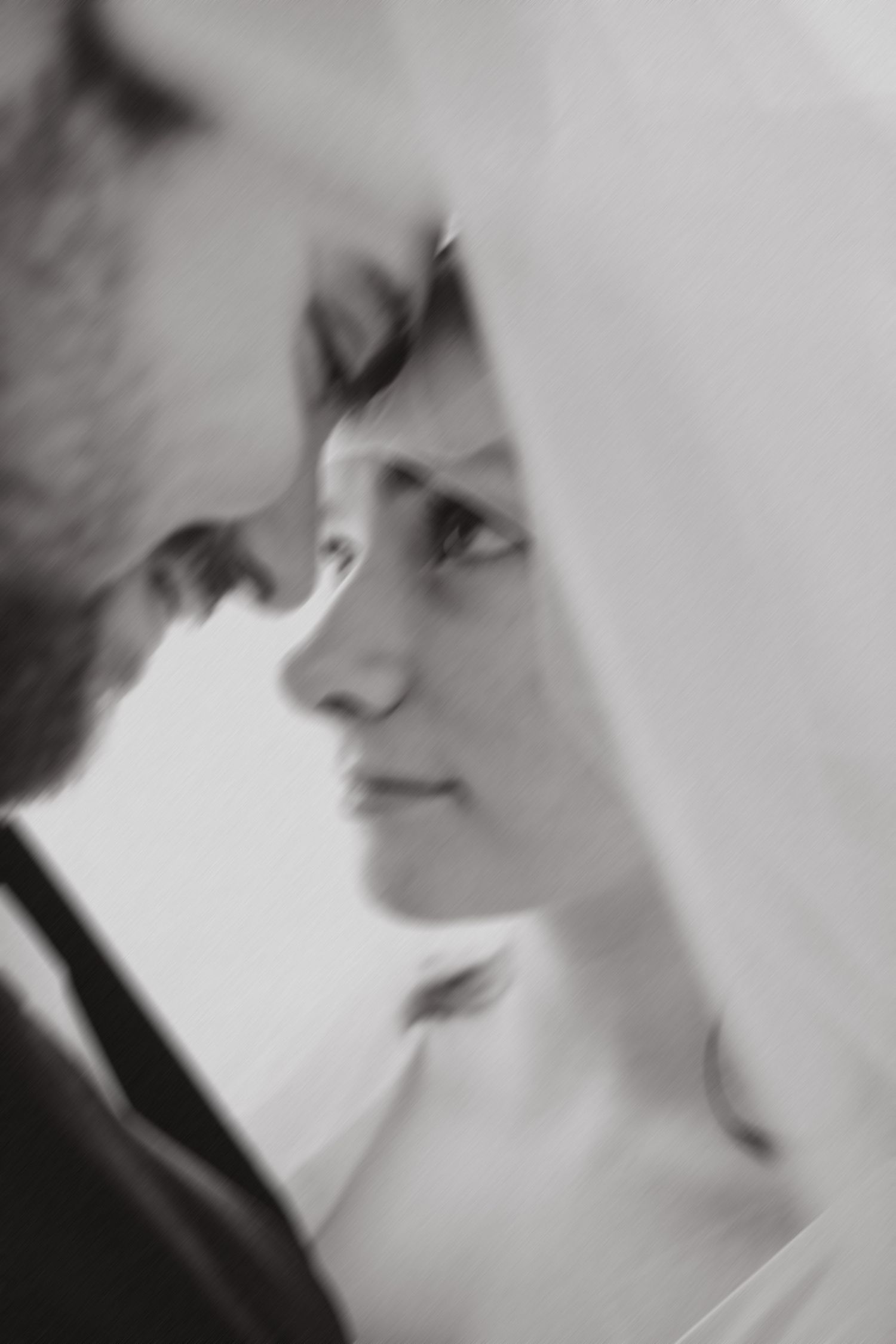black and white photo of bride and groom under veil